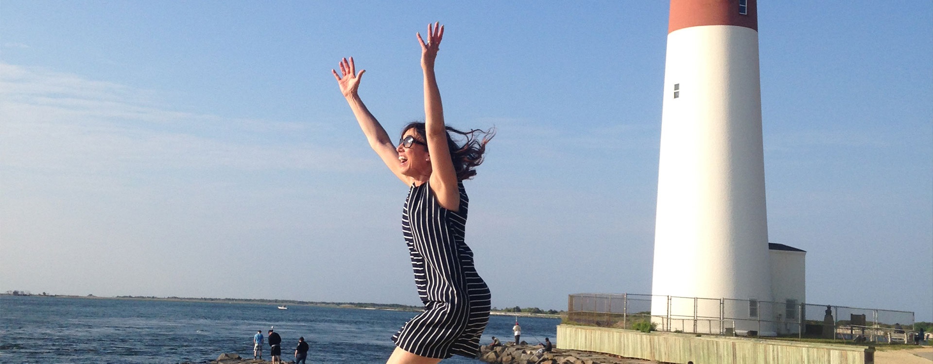 Woman running towards New Jersey shore with Barneget lighthouse in background